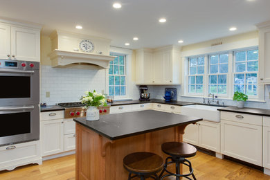 ボストンにある中くらいなおしゃれなキッチン (エプロンフロントシンク、落し込みパネル扉のキャビネット、白いキャビネット、ソープストーンカウンター、白いキッチンパネル、サブウェイタイルのキッチンパネル、パネルと同色の調理設備、無垢フローリング、茶色い床) の写真