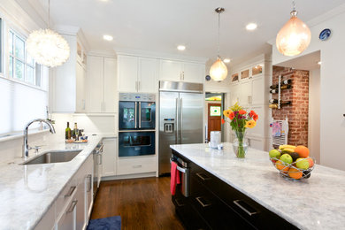 Example of a large trendy l-shaped medium tone wood floor kitchen design in New York with an undermount sink, shaker cabinets, white cabinets, marble countertops, white backsplash, subway tile backsplash, stainless steel appliances and an island