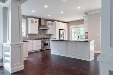 Inspiration for a large transitional l-shaped dark wood floor and brown floor open concept kitchen remodel in Tampa with shaker cabinets, white cabinets, an island, granite countertops, stainless steel appliances and a farmhouse sink