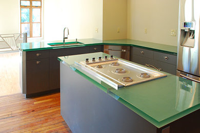 ルイビルにある高級な広いトランジショナルスタイルのおしゃれなキッチン (フラットパネル扉のキャビネット、グレーのキャビネット、ガラスカウンター、シルバーの調理設備、無垢フローリング、マルチカラーの床) の写真