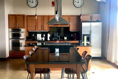 カンザスシティにあるラグジュアリーな広いコンテンポラリースタイルのおしゃれなキッチン (ダブルシンク、落し込みパネル扉のキャビネット、淡色木目調キャビネット、御影石カウンター、黒いキッチンパネル、石スラブのキッチンパネル、シルバーの調理設備、コルクフローリング、ベージュの床、黒いキッチンカウンター) の写真