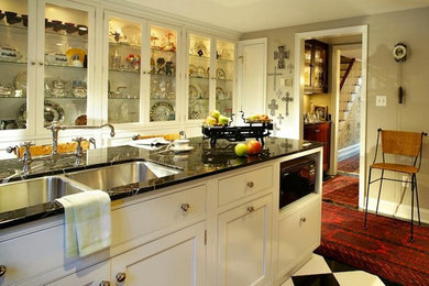 Example of a mid-sized minimalist u-shaped ceramic tile enclosed kitchen design in New York with a double-bowl sink, glass-front cabinets, white cabinets, marble countertops and an island
