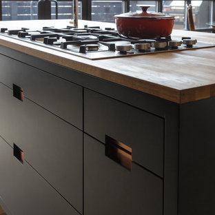 Mid-sized industrial open concept kitchen designs - Inspiration for a mid-sized industrial galley light wood floor open concept kitchen remodel in Philadelphia with an undermount sink, shaker cabinets, black cabinets, wood countertops, gray backsplash, subway tile backsplash, stainless steel appliances and an island