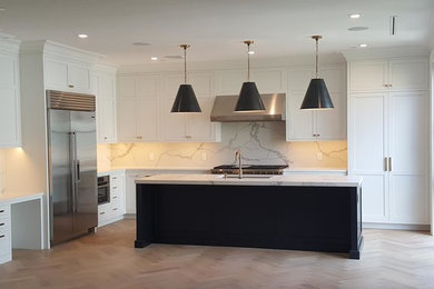 Large trendy l-shaped light wood floor and beige floor open concept kitchen photo in New York with an undermount sink, shaker cabinets, white cabinets, marble countertops, white backsplash, marble backsplash, stainless steel appliances, an island and white countertops