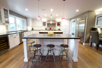 Eat-in kitchen - large contemporary u-shaped medium tone wood floor eat-in kitchen idea in San Francisco with a double-bowl sink, recessed-panel cabinets, white cabinets, granite countertops, white backsplash, subway tile backsplash, stainless steel appliances and two islands