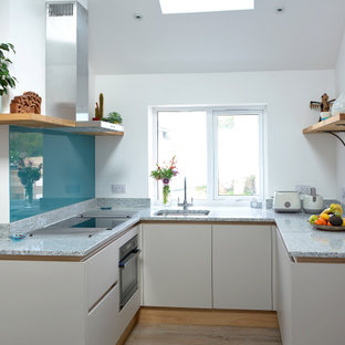 Inspiration for a small contemporary u-shaped kitchen in Cornwall with flat-panel cabinets, grey cabinets, quartz worktops, blue splashback, glass sheet splashback, black appliances, vinyl flooring, no island, brown floors, grey worktops and a submerged sink.