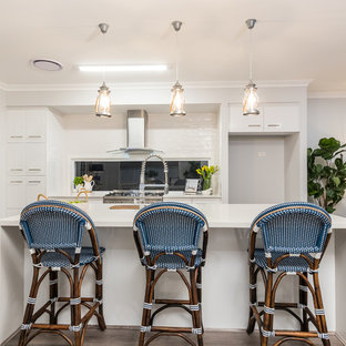 Photo of a large beach style kitchen in Brisbane with flat-panel cabinets, white cabinets, quartz benchtops, white benchtop, window splashback, dark hardwood floors and with island.