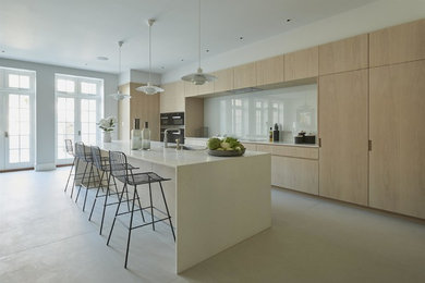 Moderne Küche mit flächenbündigen Schrankfronten, hellen Holzschränken, Küchenrückwand in Weiß, Glasrückwand und Kücheninsel in London