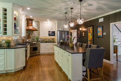 Example of a mid-sized transitional u-shaped medium tone wood floor and brown floor eat-in kitchen design in Boston with stone tile backsplash, stainless steel appliances, an island, black countertops, an undermount sink, shaker cabinets, white cabinets, soapstone countertops and brown backsplash