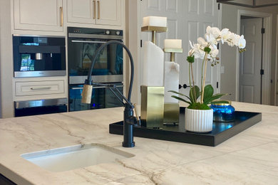 Transitional l-shaped open concept kitchen photo in San Francisco with a single-bowl sink, gray cabinets, stainless steel appliances, an island and white countertops