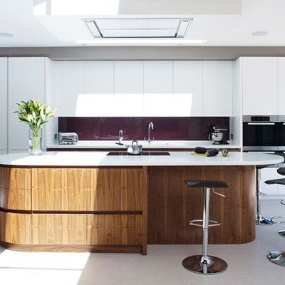 Kitchen - contemporary kitchen idea in London with flat-panel cabinets, white cabinets, glass sheet backsplash, stainless steel appliances and an island
