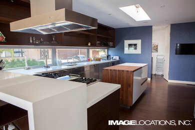 Modelo de cocina comedor contemporánea de tamaño medio con armarios abiertos, suelo de madera oscura y una isla