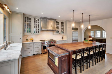 Kitchen - large traditional l-shaped medium tone wood floor kitchen idea in Birmingham with a farmhouse sink, beaded inset cabinets, marble countertops, porcelain backsplash, stainless steel appliances, an island, gray cabinets and white backsplash