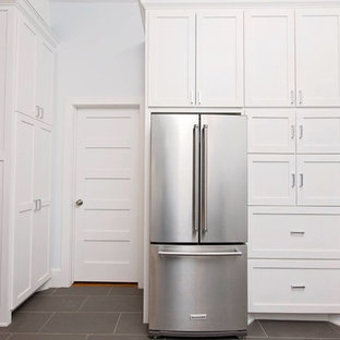 Inspiration for a medium sized farmhouse l-shaped open plan kitchen in Orange County with a belfast sink, shaker cabinets, white cabinets, quartz worktops, white splashback, metro tiled splashback, stainless steel appliances, porcelain flooring and a breakfast bar.