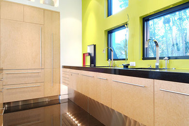 Ejemplo de cocina comedor moderna de tamaño medio con armarios con paneles lisos, puertas de armario de madera clara, encimera de granito, electrodomésticos de acero inoxidable y una isla