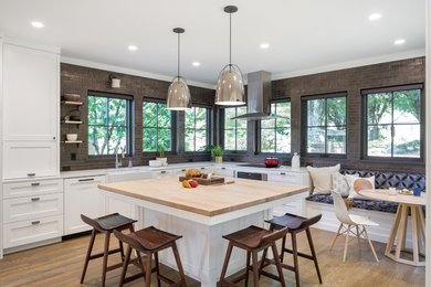 Inspiration for a transitional medium tone wood floor kitchen remodel in Portland with a farmhouse sink, shaker cabinets, white cabinets, metallic backsplash, subway tile backsplash, stainless steel appliances and an island