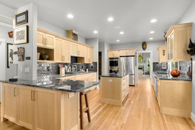 Large transitional galley light wood floor and beige floor open concept kitchen photo in Seattle with an undermount sink, shaker cabinets, light wood cabinets, granite countertops, black backsplash, subway tile backsplash, stainless steel appliances, an island and gray countertops