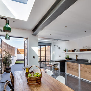 Mid-sized contemporary l-shaped eat-in kitchen in London with an integrated sink, flat-panel cabinets, medium wood cabinets, concrete benchtops, black splashback, cement tile splashback, panelled appliances, concrete floors and a peninsula.