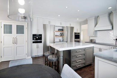Bild på ett stort funkis vit vitt kök, med en undermonterad diskho, luckor med infälld panel, vita skåp, bänkskiva i kvartsit, vitt stänkskydd, stänkskydd i keramik, rostfria vitvaror, mörkt trägolv, en köksö och brunt golv