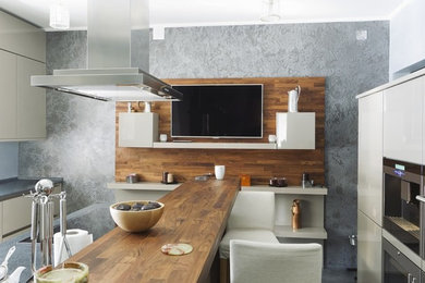 Foto de cocina actual de tamaño medio abierta con armarios con paneles lisos, puertas de armario blancas, encimera de madera, electrodomésticos de acero inoxidable y una isla