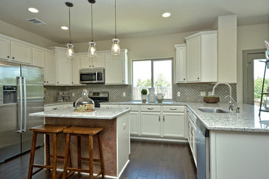 Example of a mid-sized cottage u-shaped dark wood floor kitchen design in Austin with an undermount sink, recessed-panel cabinets, white cabinets, granite countertops, green backsplash, porcelain backsplash, stainless steel appliances and an island