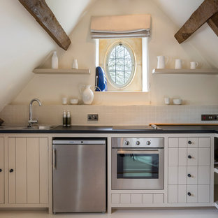 Inspiration for a small country l-shaped enclosed kitchen in Gloucestershire with a built-in sink, beige cabinets, beige splashback, stainless steel appliances, no island, beige floors and black worktops.