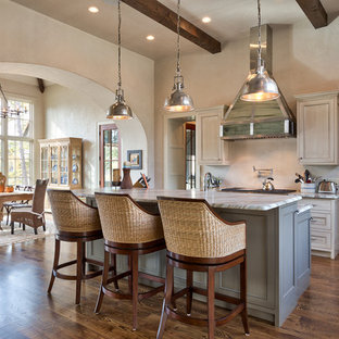 Photo of a mid-sized beach style galley eat-in kitchen in Other with beige cabinets, granite benchtops, beige splashback, dark hardwood floors, with island and recessed-panel cabinets.