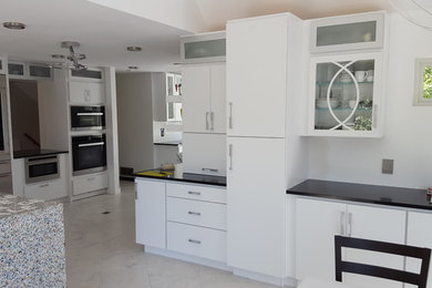 Photo of an expansive contemporary single-wall kitchen/diner in Minneapolis with flat-panel cabinets, white cabinets, white splashback, stainless steel appliances, marble flooring, an island, grey floors and engineered stone countertops.