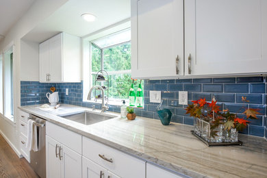 Large transitional galley medium tone wood floor and brown floor open concept kitchen photo in Orange County with an undermount sink, shaker cabinets, white cabinets, quartz countertops, blue backsplash, subway tile backsplash, stainless steel appliances, an island and multicolored countertops