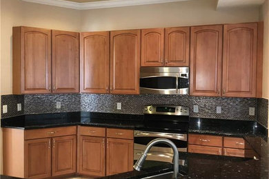 Kitchen photo in Miami with raised-panel cabinets, brown cabinets and granite countertops