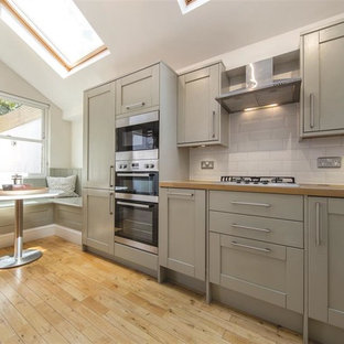 Photo of a small contemporary l-shaped kitchen in London with grey cabinets, wood worktops, white splashback, stainless steel appliances, light hardwood flooring, no island, beige floors, beige worktops and recessed-panel cabinets.