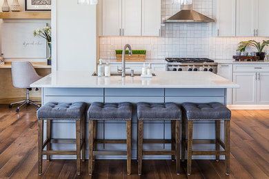 Eat-in kitchen - large transitional l-shaped medium tone wood floor and brown floor eat-in kitchen idea in Other with an undermount sink, shaker cabinets, white cabinets, quartz countertops, white backsplash, subway tile backsplash, stainless steel appliances and an island