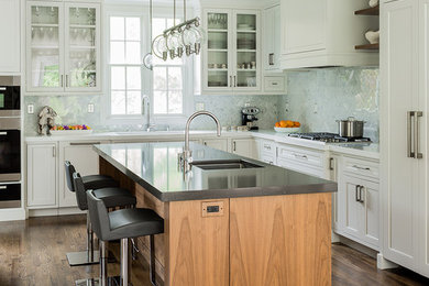 Example of a transitional l-shaped dark wood floor kitchen design in Boston with an undermount sink, recessed-panel cabinets, white cabinets, quartz countertops, white backsplash, stone tile backsplash, paneled appliances and an island