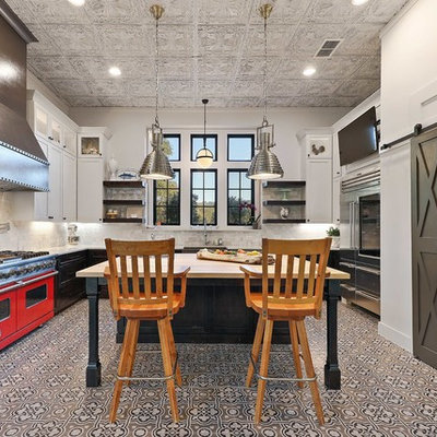 Example of a country u-shaped cement tile floor and multicolored floor kitchen design in Austin with shaker cabinets, black cabinets, white backsplash, stainless steel appliances, an island and white countertops