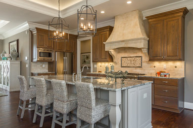 Example of a large transitional l-shaped medium tone wood floor open concept kitchen design in Louisville with an undermount sink, raised-panel cabinets, medium tone wood cabinets, granite countertops, beige backsplash, stone tile backsplash, stainless steel appliances and an island