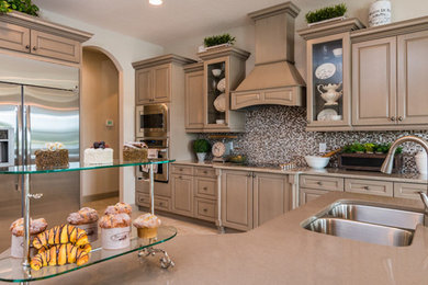 Inspiration for a large timeless u-shaped kitchen remodel in Orlando with raised-panel cabinets, brown cabinets, an island, a double-bowl sink, solid surface countertops, multicolored backsplash, glass tile backsplash and stainless steel appliances