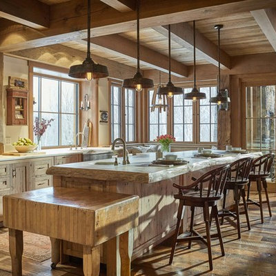 Mountain style medium tone wood floor and brown floor eat-in kitchen photo in Burlington with a farmhouse sink, shaker cabinets, wood countertops, gray backsplash, stone tile backsplash, stainless steel appliances, an island, beige countertops and light wood cabinets