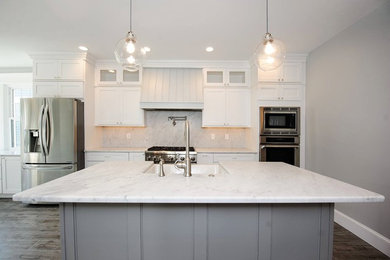 Example of a large transitional single-wall porcelain tile and brown floor eat-in kitchen design in Philadelphia with a farmhouse sink, recessed-panel cabinets, white cabinets, marble countertops, white backsplash, marble backsplash, stainless steel appliances and an island