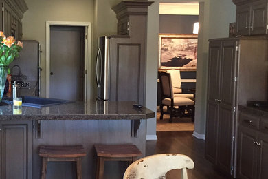 Example of a mid-sized classic l-shaped dark wood floor and brown floor eat-in kitchen design in Kansas City with a drop-in sink, granite countertops, stainless steel appliances, a peninsula, raised-panel cabinets and gray cabinets