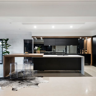 Contemporary l-shaped eat-in kitchen in Gold Coast - Tweed with an undermount sink, flat-panel cabinets, black cabinets, wood benchtops, metallic splashback, mirror splashback, black appliances, with island and beige floor.