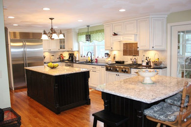 Example of a large classic l-shaped dark wood floor eat-in kitchen design in Providence with an undermount sink, raised-panel cabinets, white cabinets, granite countertops, white backsplash, subway tile backsplash, stainless steel appliances and two islands