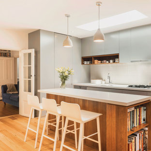 Contemporary kitchen in Sydney with an undermount sink, flat-panel cabinets, grey cabinets, white splashback, mosaic tile splashback, light hardwood floors, with island, beige floor and white benchtop.