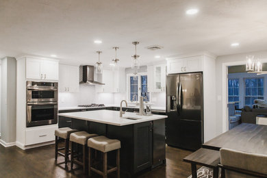 Example of a mid-sized minimalist dark wood floor and brown floor kitchen design in Boston with shaker cabinets, black cabinets, marble countertops, gray backsplash, ceramic backsplash, stainless steel appliances, an island and white countertops