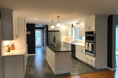 Example of a mid-sized transitional galley porcelain tile and gray floor eat-in kitchen design in Boston with an undermount sink, shaker cabinets, white cabinets, quartz countertops, white backsplash, porcelain backsplash, stainless steel appliances and an island