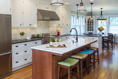 Mid-sized transitional l-shaped medium tone wood floor eat-in kitchen photo in Minneapolis with a farmhouse sink, beaded inset cabinets, white cabinets, subway tile backsplash, stainless steel appliances, an island, beige backsplash and marble countertops