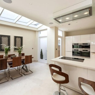 Design ideas for a medium sized modern u-shaped kitchen/diner in London with a submerged sink, flat-panel cabinets, white cabinets, mirror splashback, stainless steel appliances, a breakfast bar, white worktops and white floors.