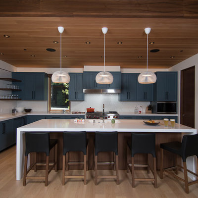 Mid-sized minimalist u-shaped light wood floor and beige floor open concept kitchen photo in Sacramento with an integrated sink, flat-panel cabinets, blue cabinets, quartz countertops, white backsplash, porcelain backsplash, paneled appliances, an island and white countertops