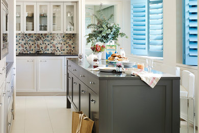 Ejemplo de cocina tradicional renovada con armarios estilo shaker, puertas de armario blancas, salpicadero multicolor y una isla