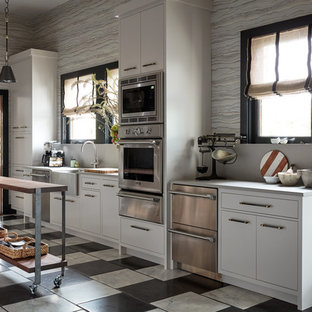 Diseño de cocina de galera, actual, con salpicadero verde, dos o más islas, fregadero sobremueble, armarios con paneles lisos, puertas de armario blancas, electrodomésticos de acero inoxidable y suelo multicolor