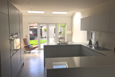 This is an example of a contemporary kitchen in Belfast with flat-panel cabinets, ceramic flooring and an island.